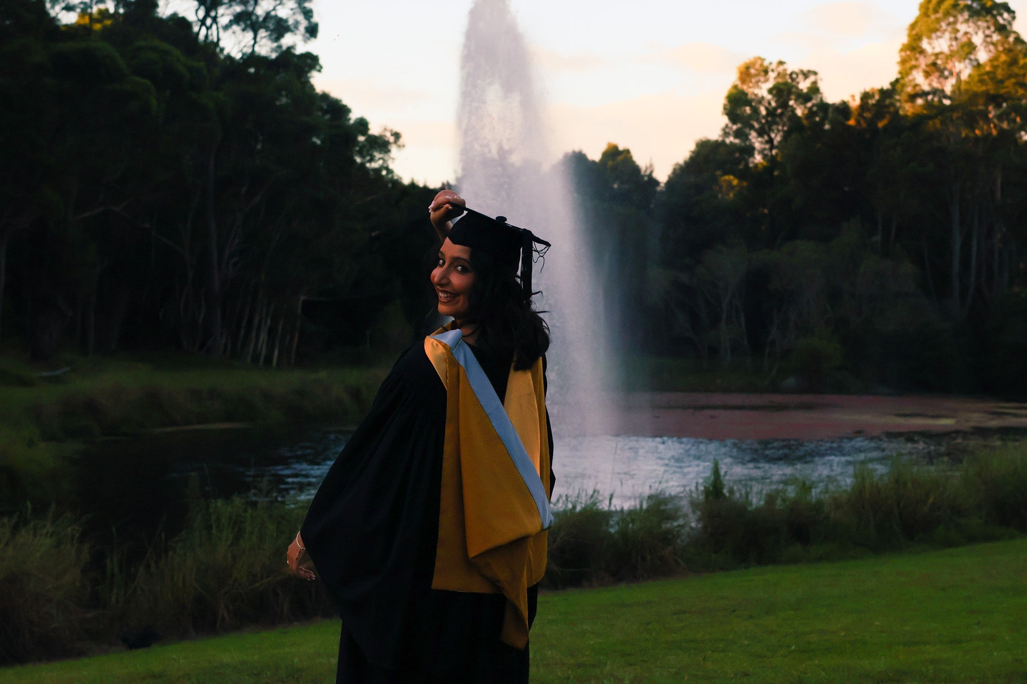 Graduate looking back toward the camera in front of a fountain