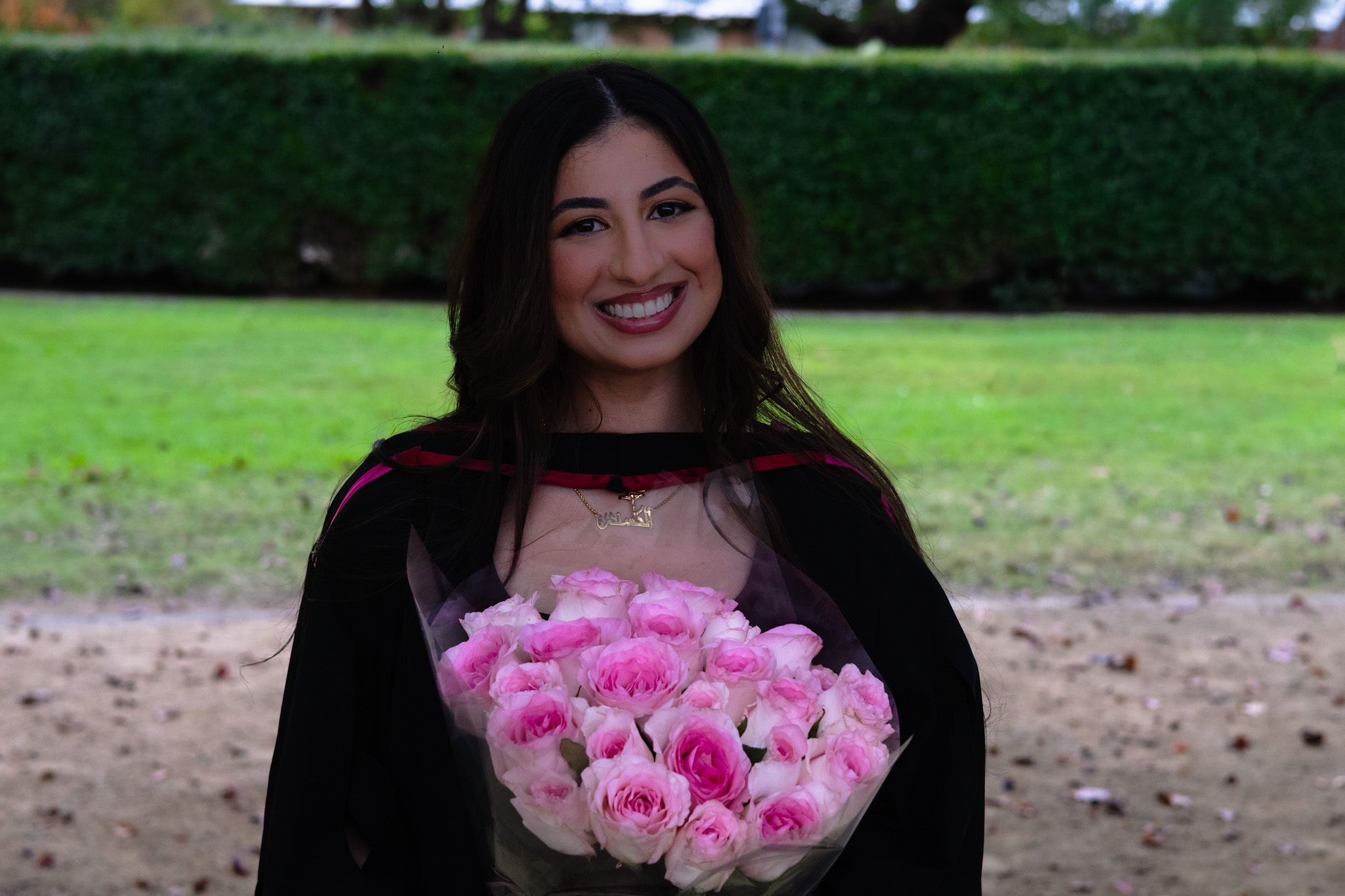 Graduate smiling with a bouquet of pink roses