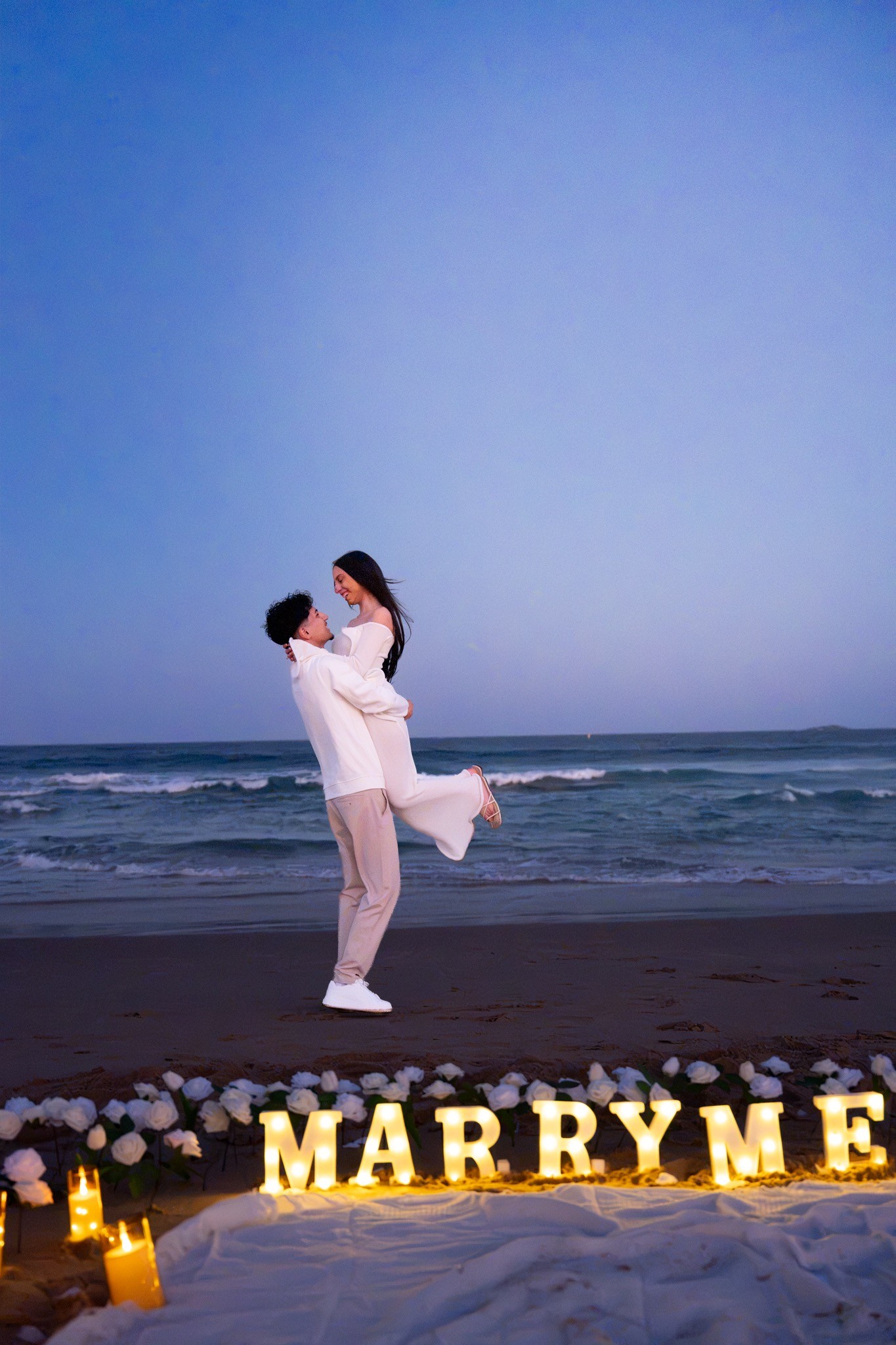 Couple celebrating with a playful lift near the proposal setup